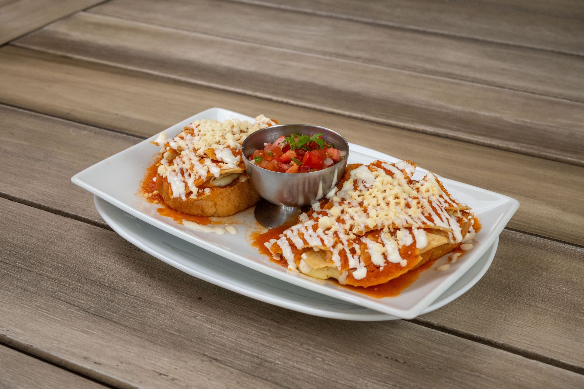 Delicious enchiladas topped with cheese and served with fresh salsa in a Mexican restaurant.
